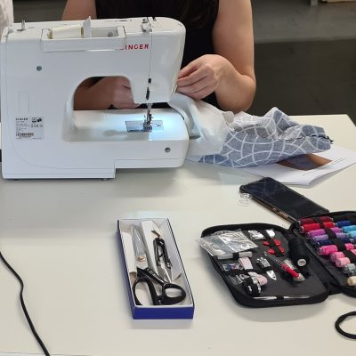 Une machine à coudre avec des ciseaux et des bobines de fils sont devant une élève qui a pris des cours de couture à Brie Comte Robert.